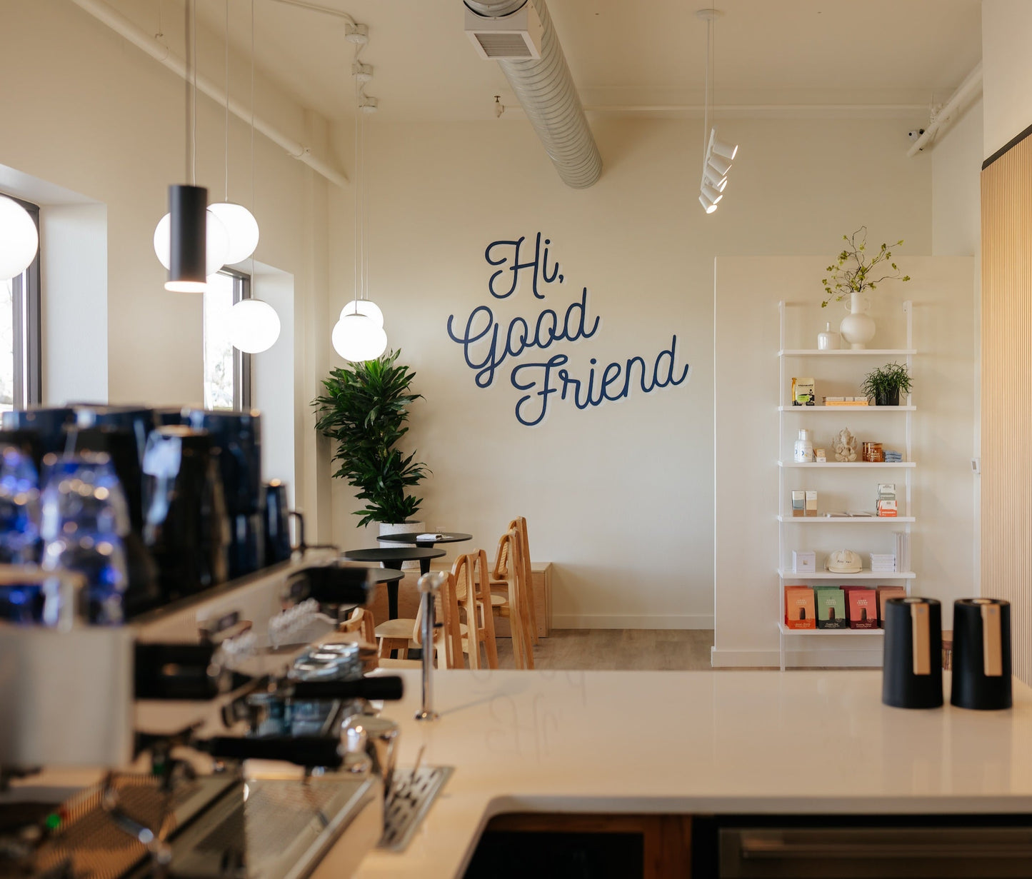 Modern bakehouse and coffee bar with 'Hi, Good Friend' wall text and tables for seating.