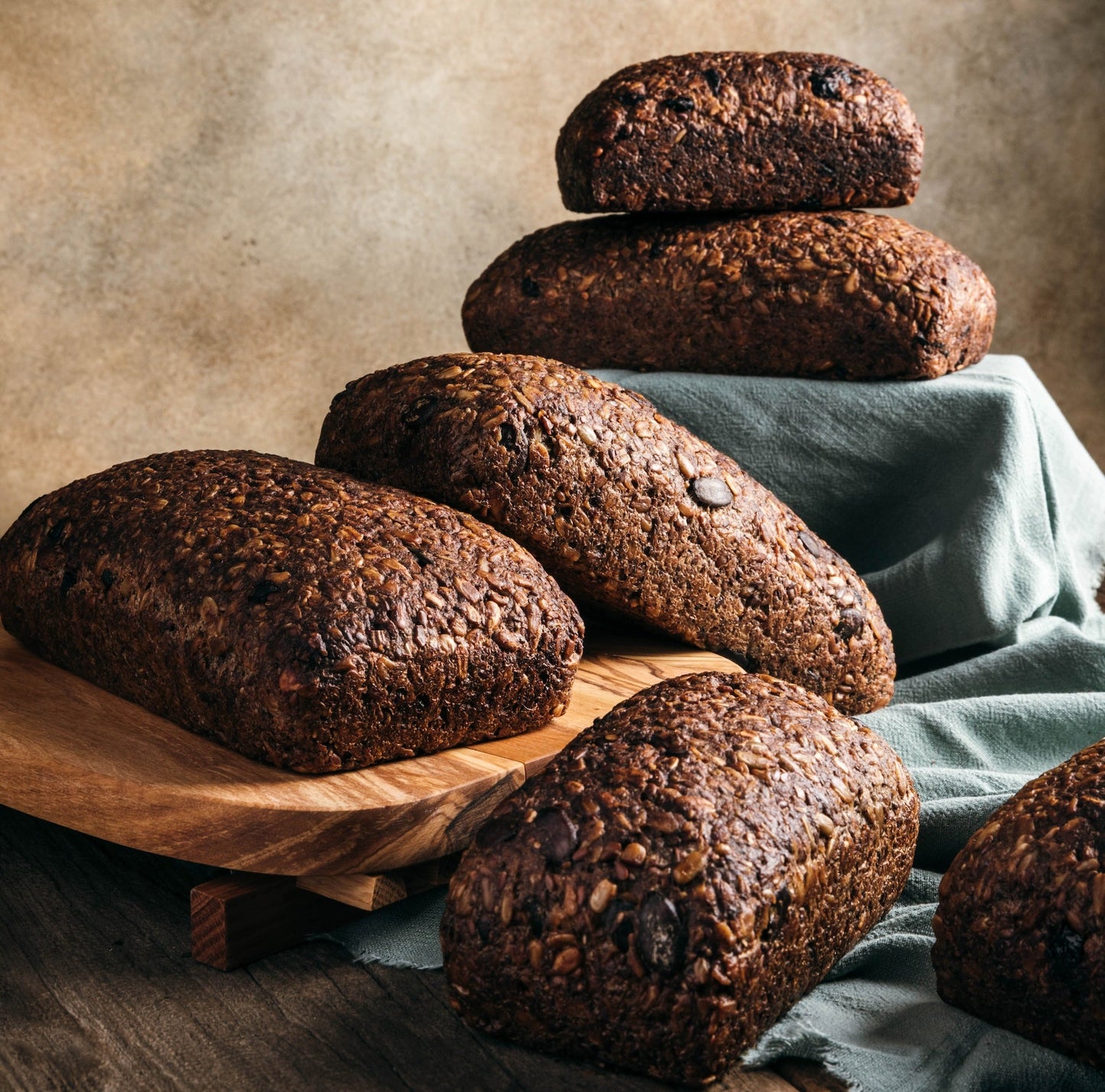 Assorted loaves of dark bread on a wooden surface with a textured background
