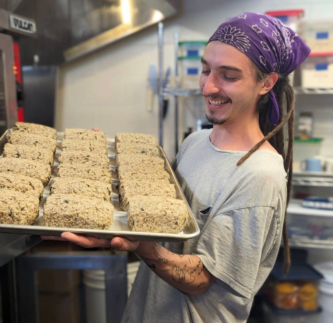 Person holding a tray of baked goods in a kitchen setting